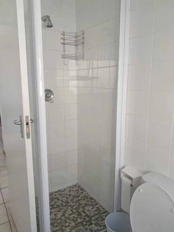 Modern shower stall with glass enclosure and white tile walls