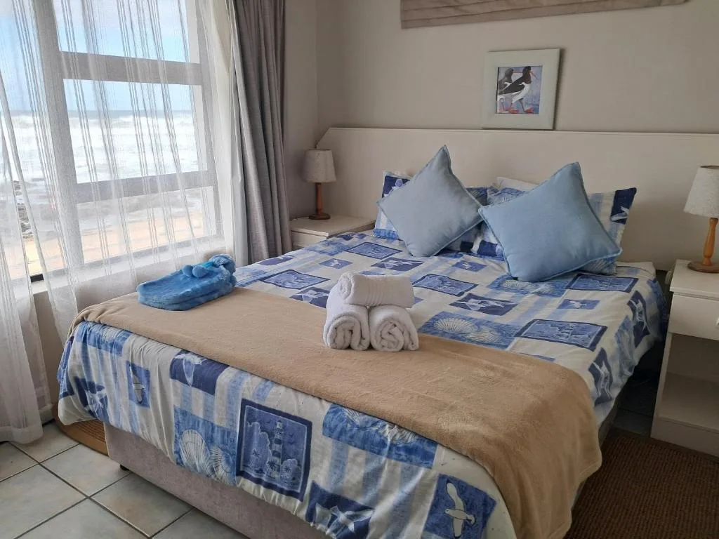Bright bedroom with double bed, ocean view through large windows