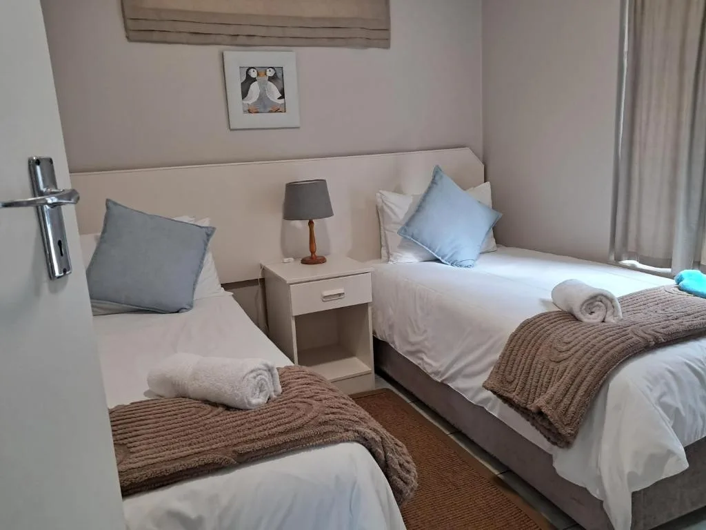 Twin bedroom with neutral decor, bedside lamp, and rolled towels