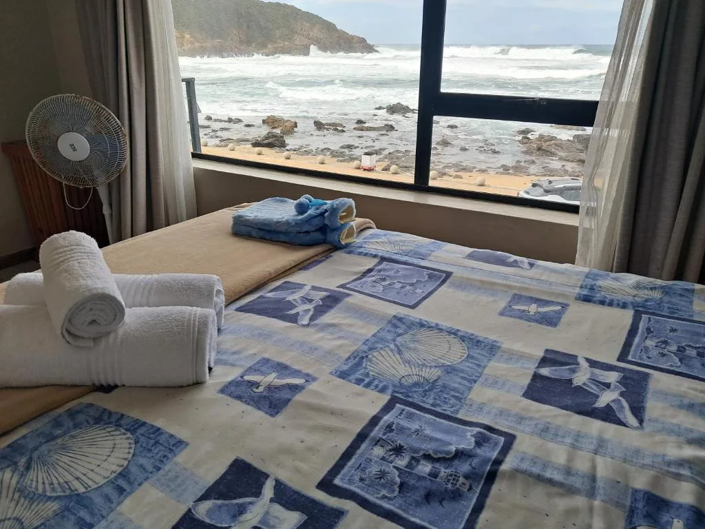 Bedroom with ocean view, bed with blue patterned bedding, rolled towels