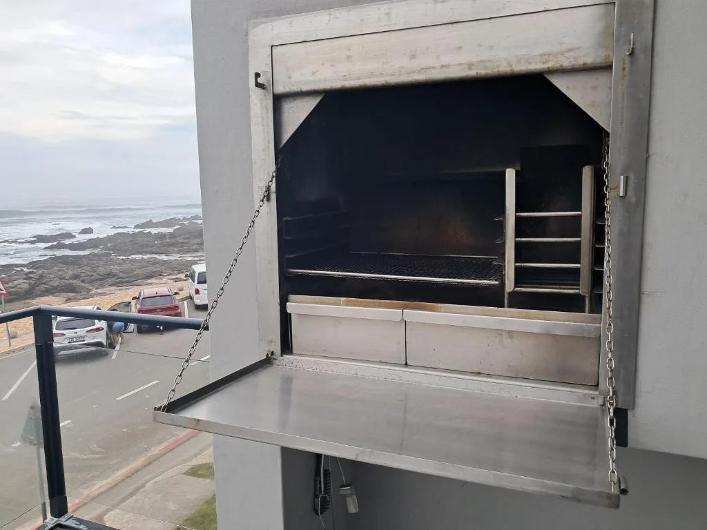 Built-in braai with ocean and coastal rocks visible in background