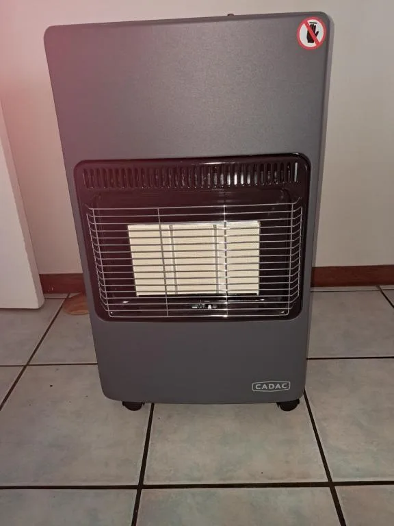 Portable gas heater with safety valve, standing on tiled floor indoors