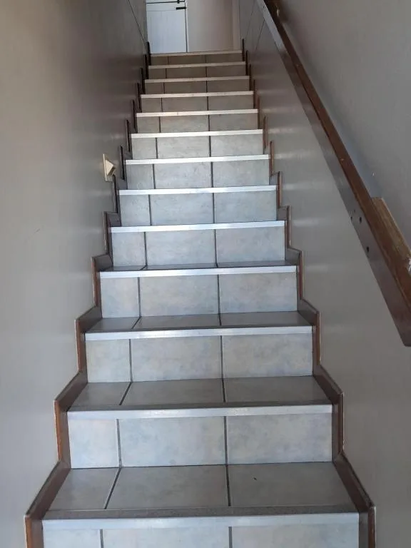 Interior staircase with tiled steps and wooden handrails leading upward