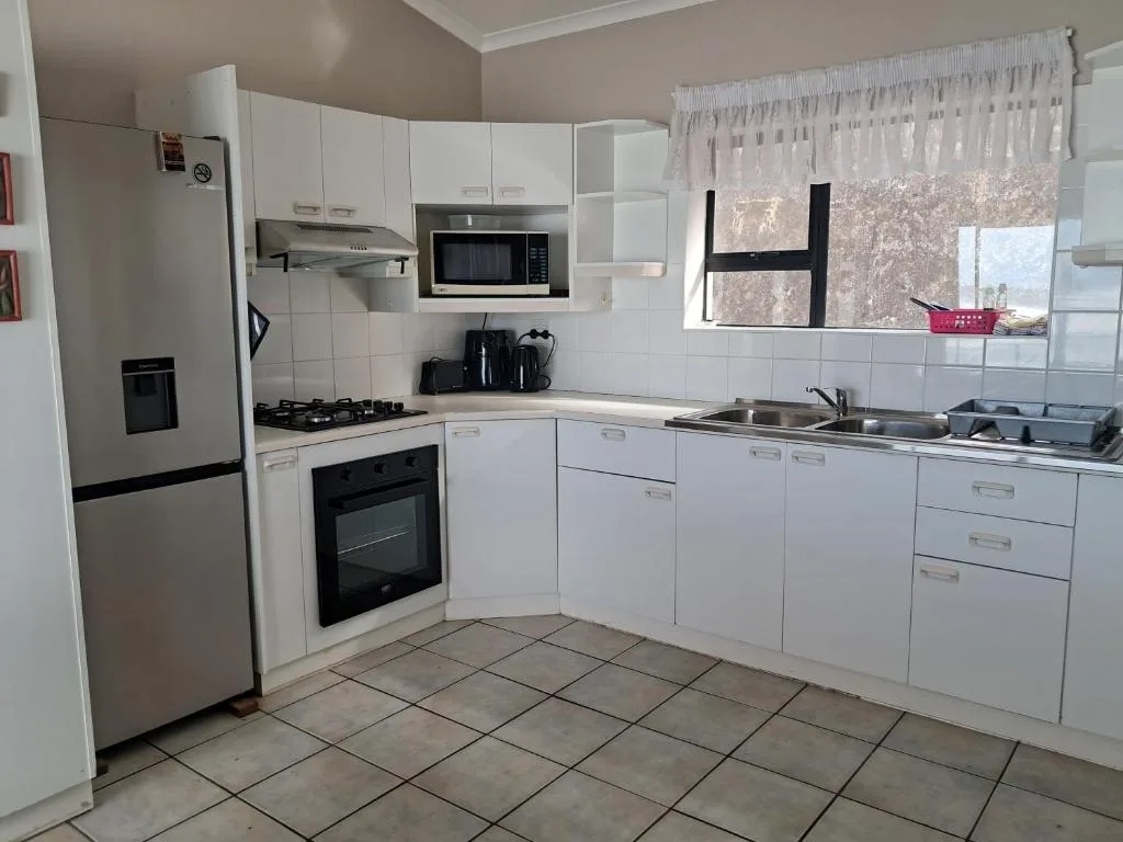 Modern white kitchen with stainless steel appliances and tile flooring