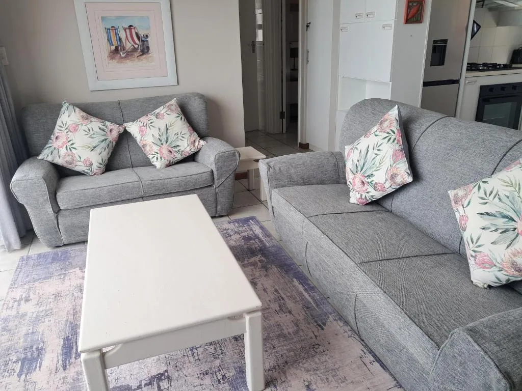 Spacious living room with gray sofas, floral pillows, white coffee table