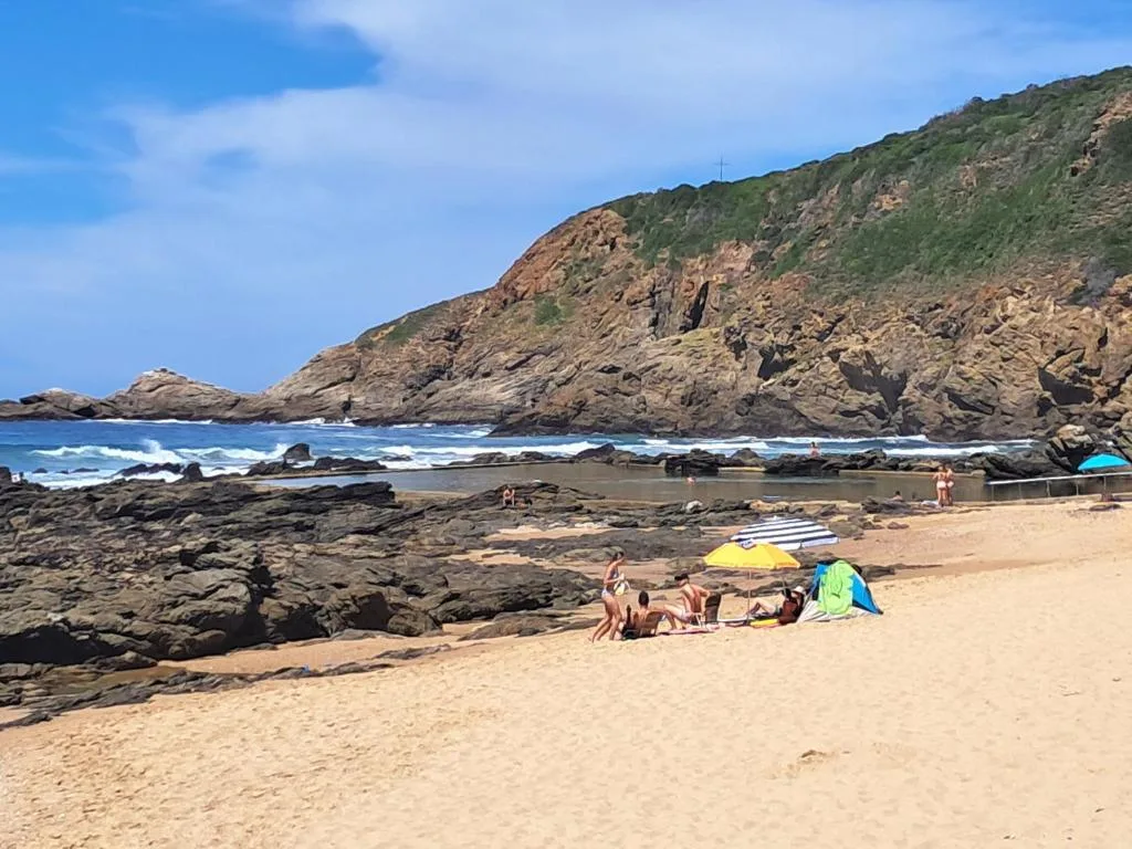 Scenic rocky beach cove with turquoise ocean waves and dramatic cliff formations
