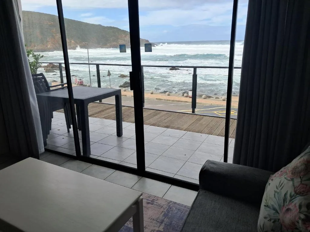 Ocean waves and rocky coastline visible through large glass doors from interior