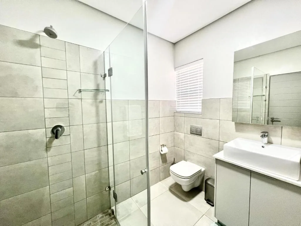 Modern bathroom with walk-in shower, toilet, and vanity sink with mirror