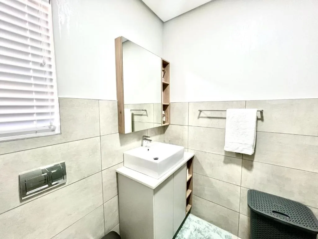 Modern bathroom with white vessel sink, mirrored cabinet, and tiled walls