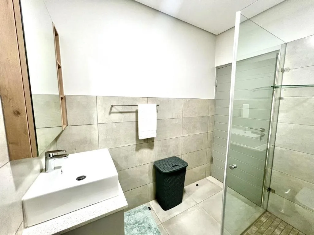 Modern bathroom with white vanity sink, glass shower enclosure, and tiled walls