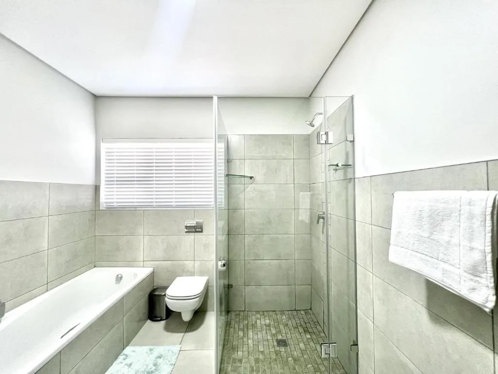 Modern bathroom with walk-in shower, bathtub, and toilet fixtures