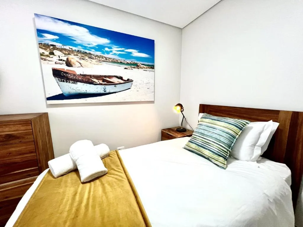 Bright bedroom with wooden bed frame and coastal artwork above headboard