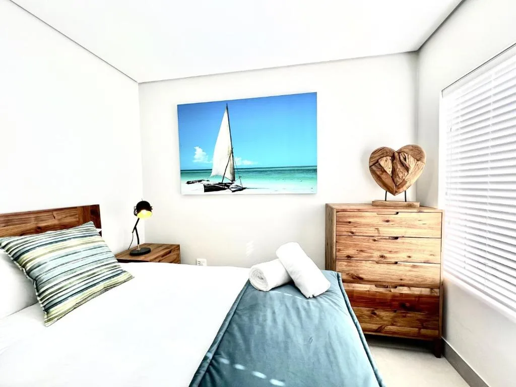 Bright bedroom with wooden furniture and coastal sailboat artwork on wall