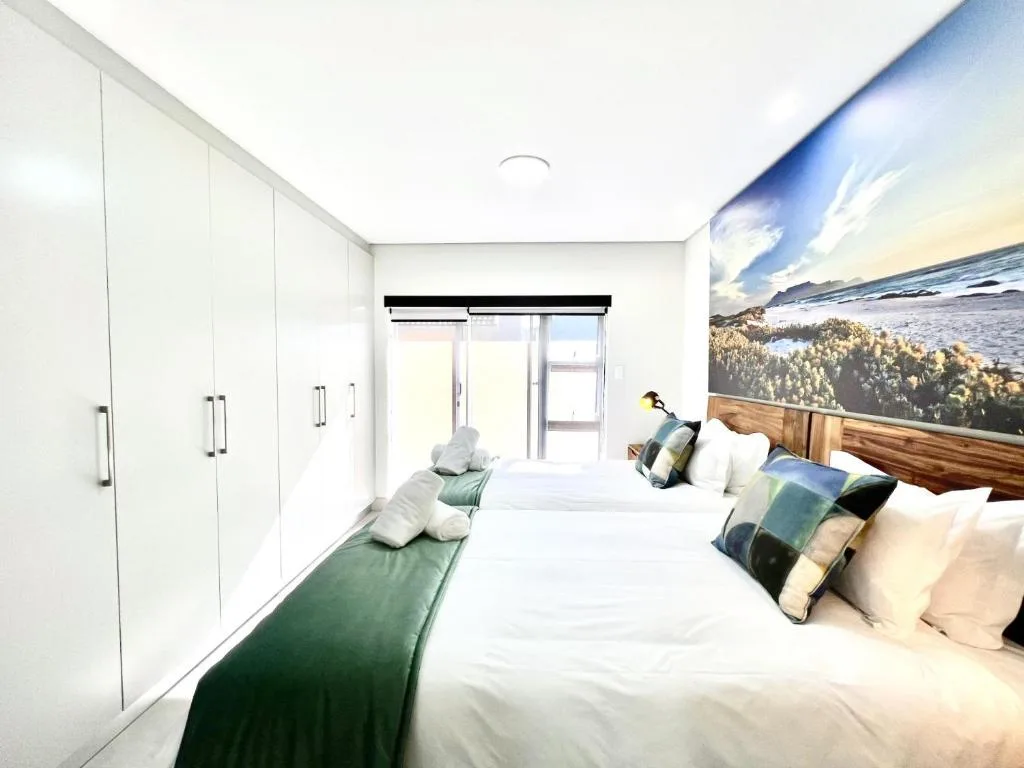 Modern bedroom with twin beds, white cabinetry, and coastal artwork
