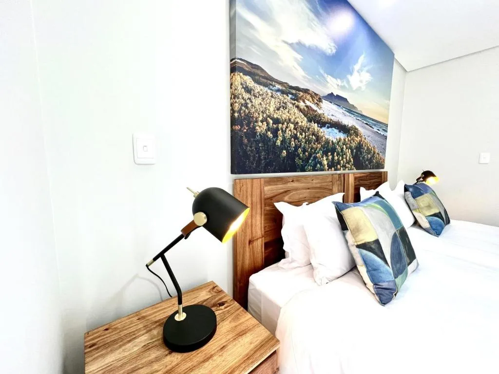 Modern bedroom with twin beds, wooden headboard, and mountain landscape artwork