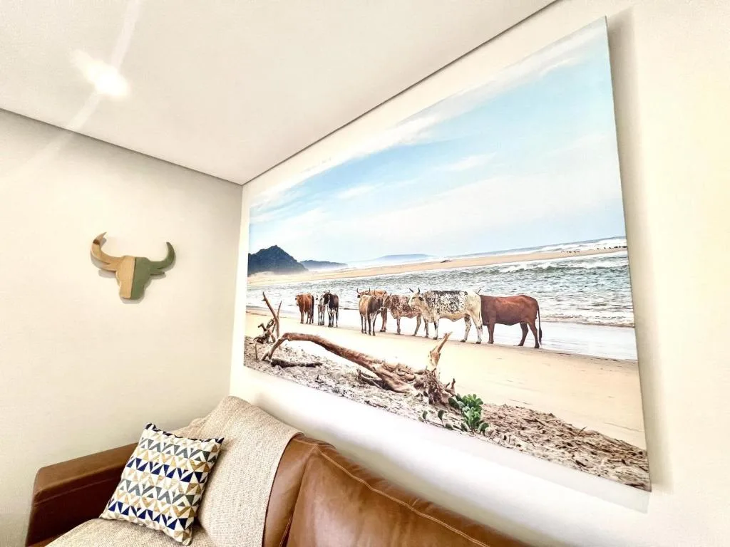 Coastal landscape artwork featuring cattle on beach displayed indoors