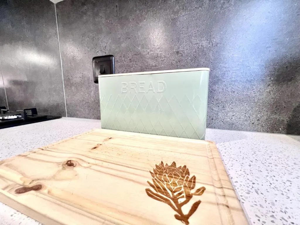Mint bread bin and engraved wooden cutting board on kitchen counter