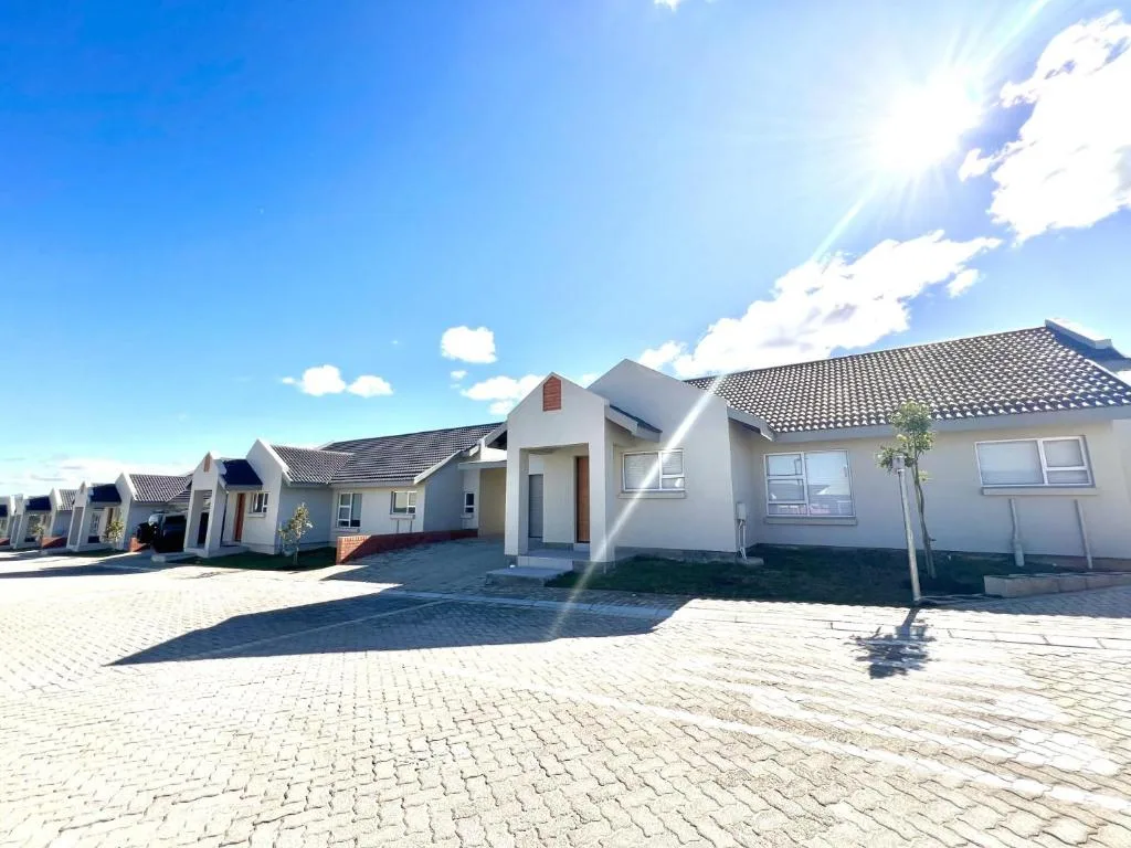 Modern white holiday cottage with dark tiled roof and paved driveway