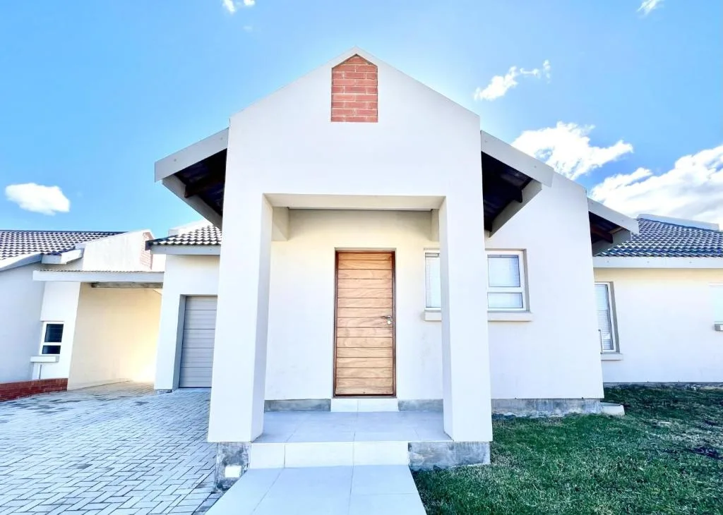 Modern white house entrance with wooden door and brick chimney detail