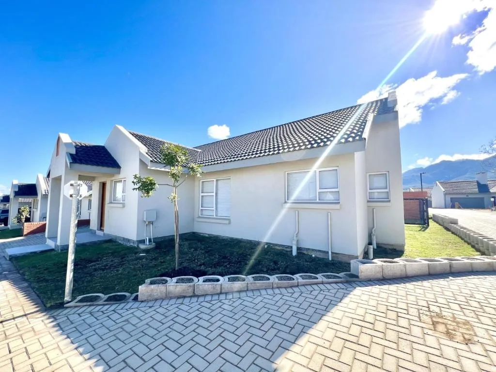 Modern white holiday cottage with dark tiled roof and paved driveway