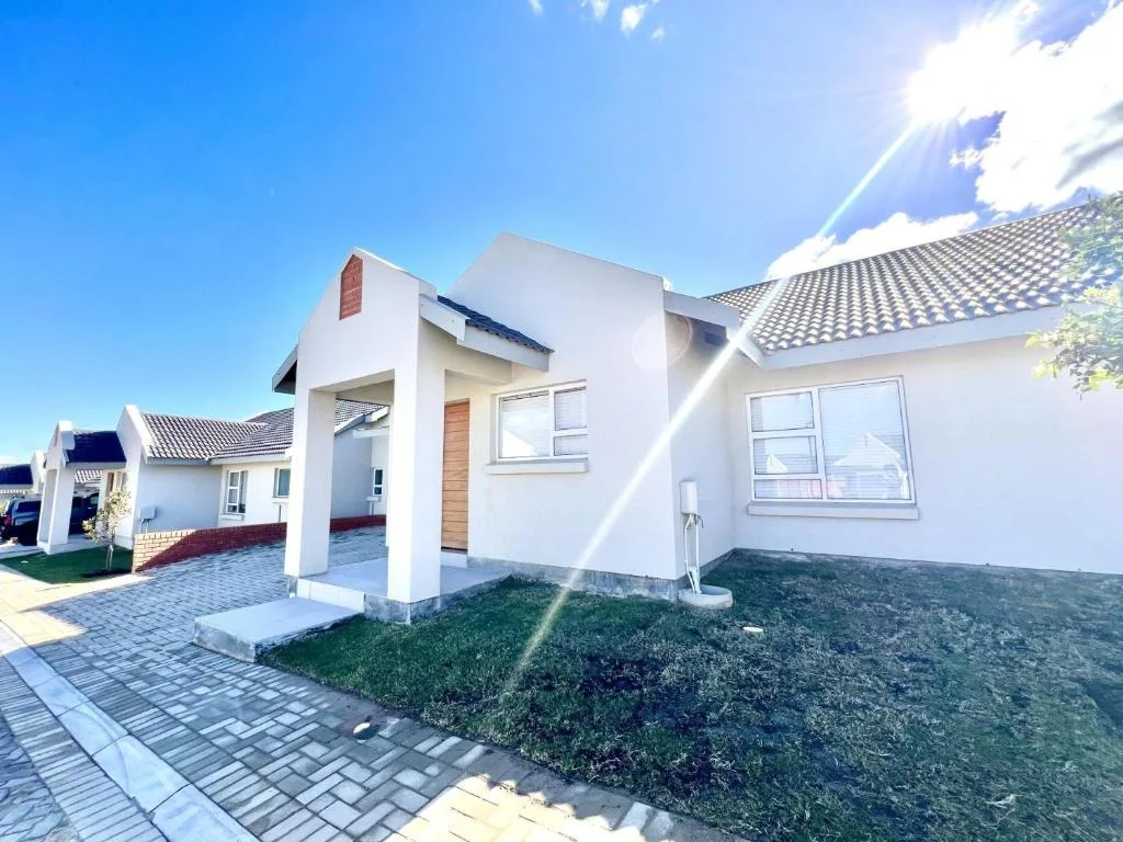 Modern white-walled house with paved driveway and manicured garden area