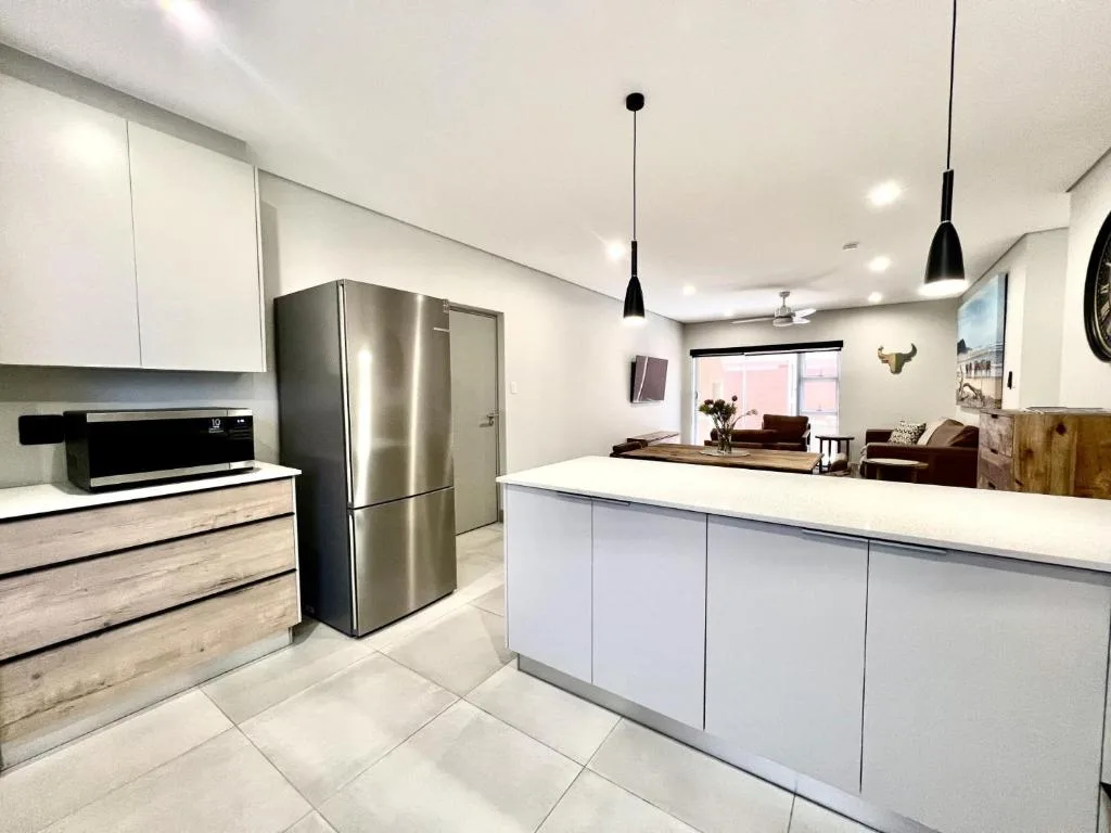 Modern kitchen with stainless steel fridge, white cabinetry, island counter