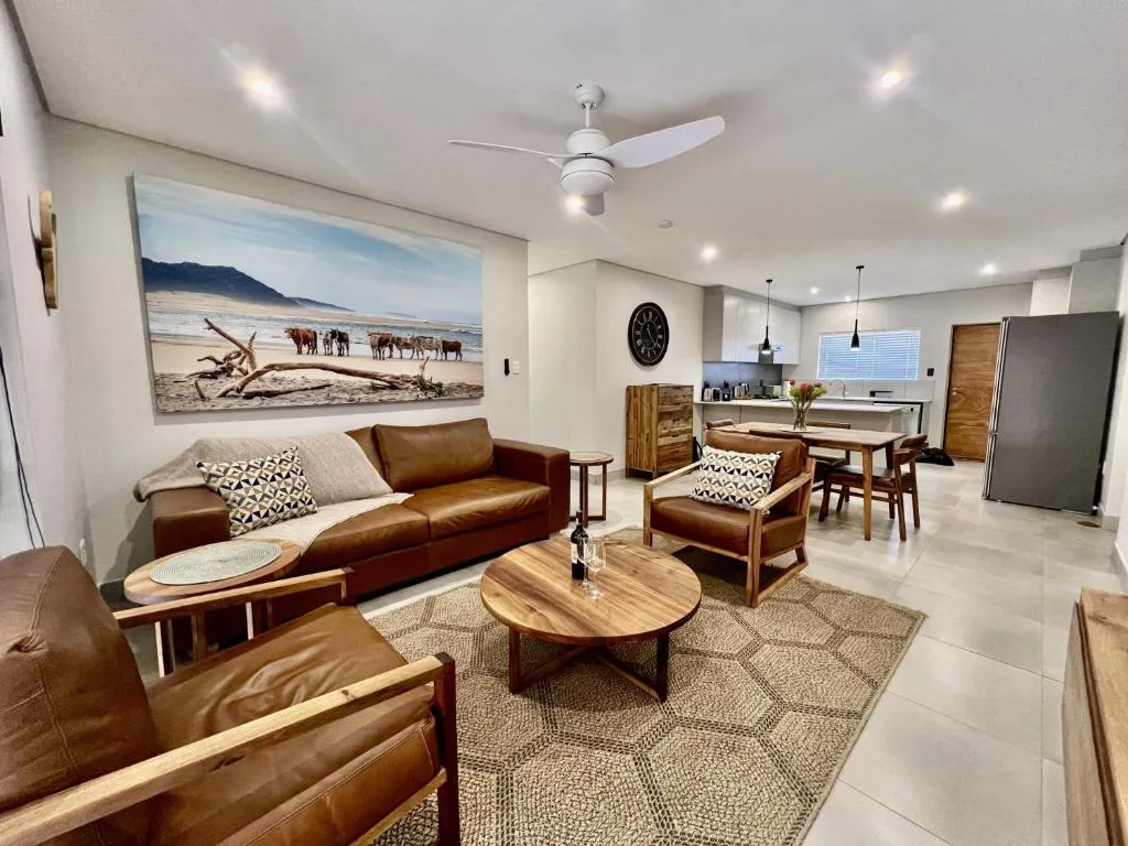 Modern lounge with brown leather sofa, wooden coffee table, and beach artwork