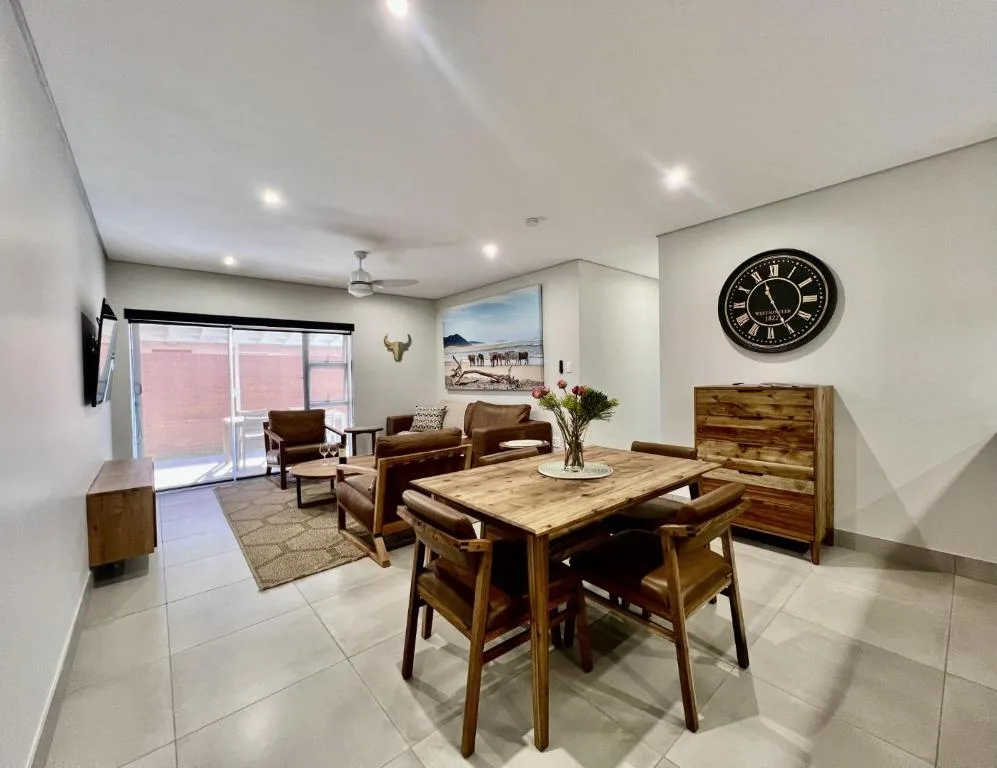 Open-plan lounge and dining area with wooden furniture and large windows