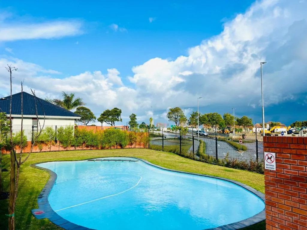 Sparkling blue swimming pool in manicured garden with brick boundary wall