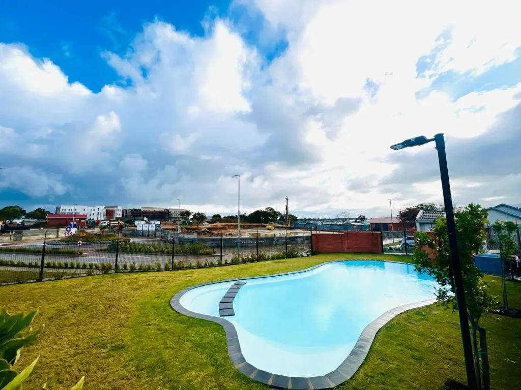 Bright blue kidney-shaped swimming pool surrounded by manicured lawn and fencing