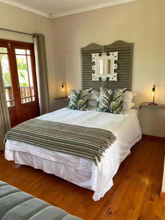 Bright bedroom with queen bed, decorative headboard, and garden view doors