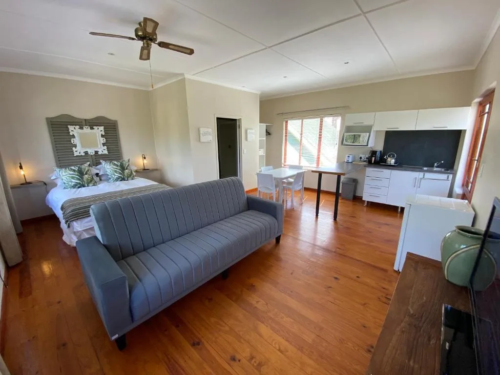 Spacious bedroom with sofa, bed, kitchenette, and wooden flooring