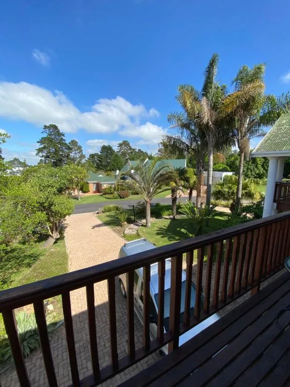 Black wooden deck railing overlooking manicured gardens and driveway