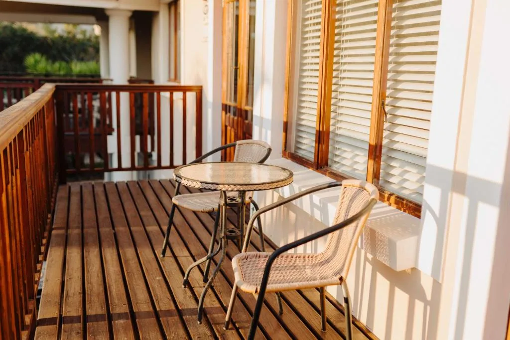 Wooden deck with round table and wicker chairs, shuttered doors