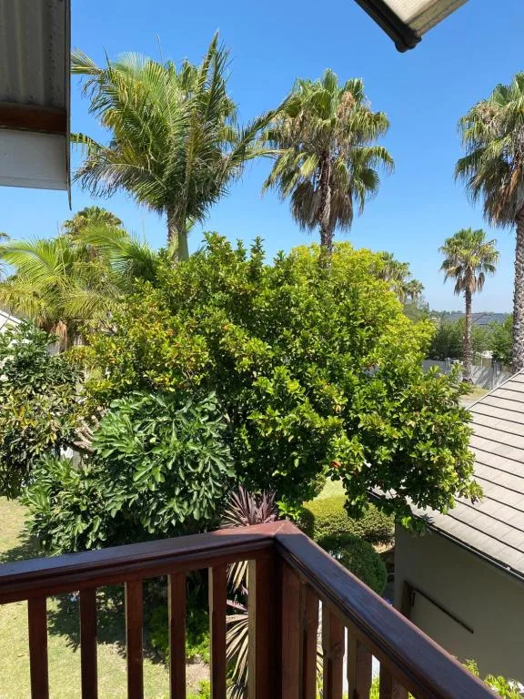 Wooden deck railing overlooking lush gardens and palm trees