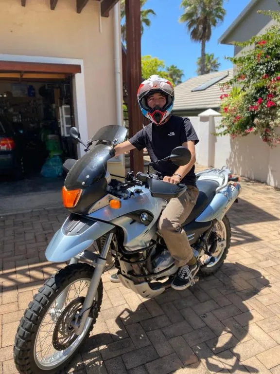 Person on motorcycle in driveway with property building and palm trees