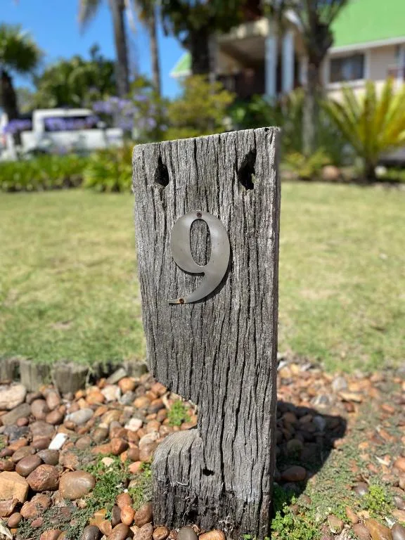 Weathered wooden property number marker nine in garden setting