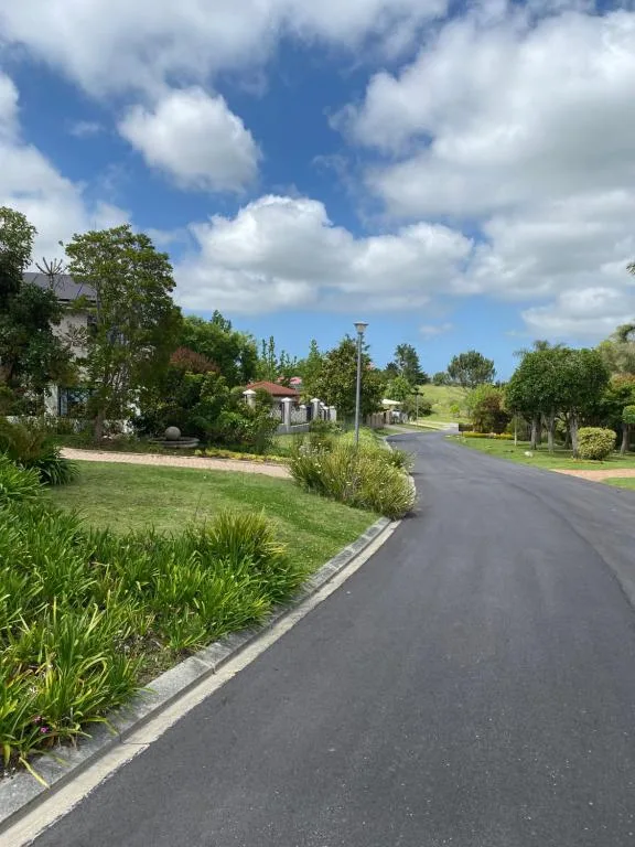 Driveway approach with manicured gardens and property entrance under blue sky