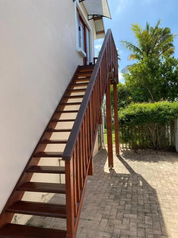 Wooden staircase with metal railing leading to property entrance