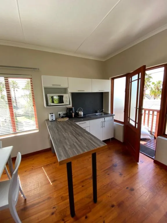 Modern kitchen with white cabinetry, island counter, and open doors to deck