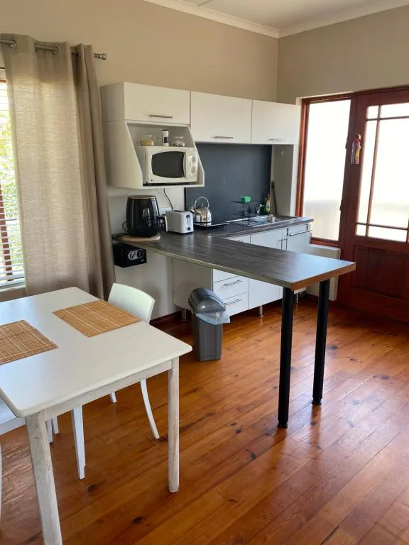 Open-plan kitchen with white cabinetry, microwave, and dining table