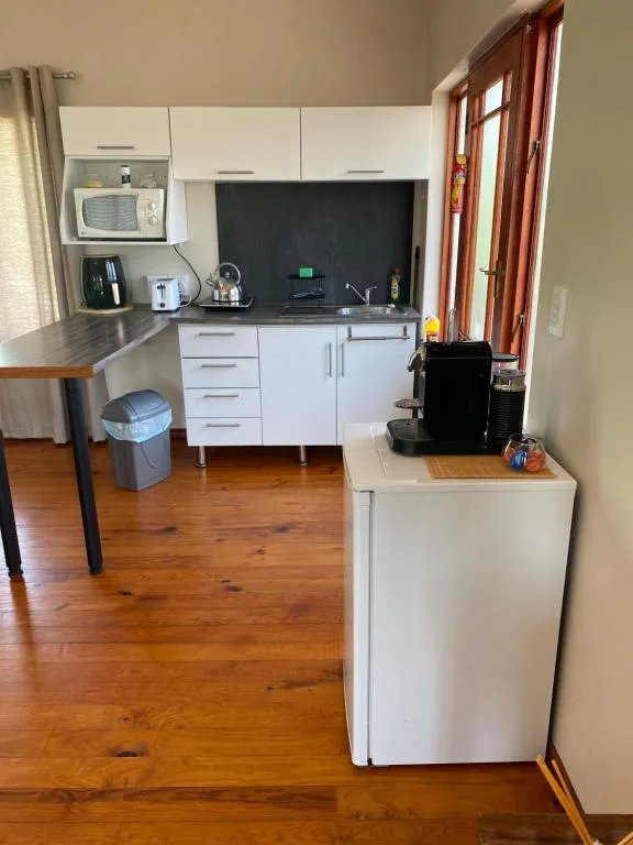 Modern kitchen with white cabinetry, black backsplash, and wooden flooring