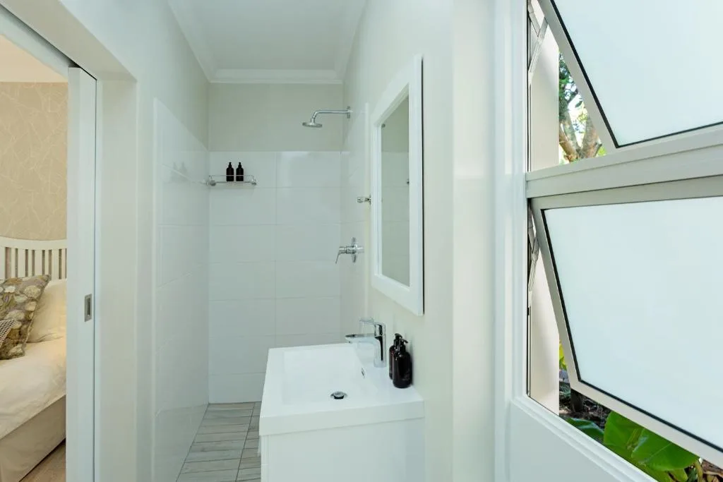 Clean white bathroom with walk-in shower and modern sink vanity