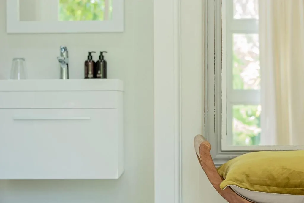 Clean white bathroom vanity with toiletries and natural window light