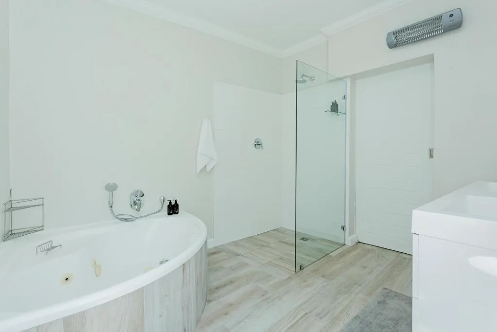 Modern bathroom with curved vanity, walk-in shower, and heated towel rail