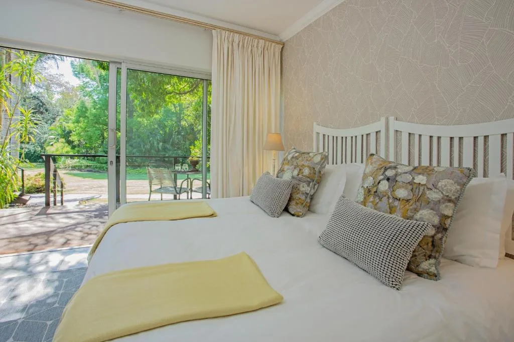 Bright bedroom with white bed, garden views through sliding doors, and deck access