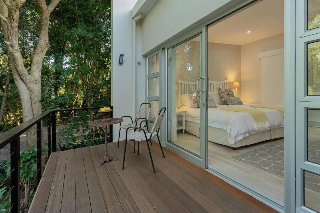 Wooden deck with seating overlooking lush garden and bedroom access
