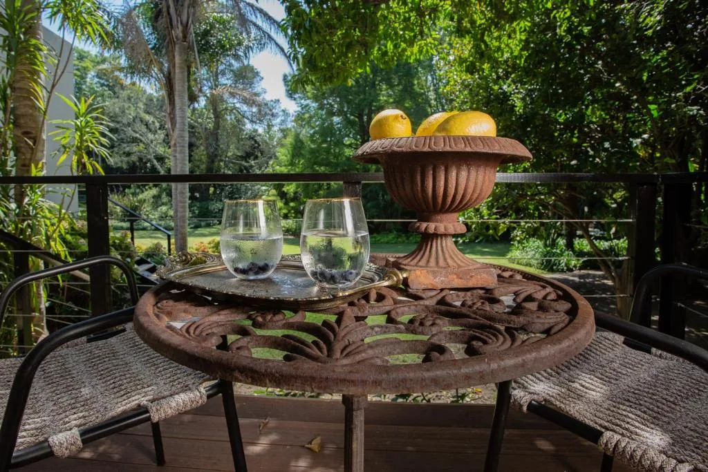 Ornate wooden table with water glasses and fruit urn on garden deck