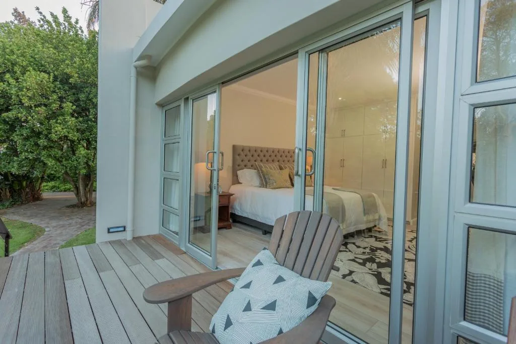 Wooden deck with Adirondack chair overlooking bedroom through glass doors