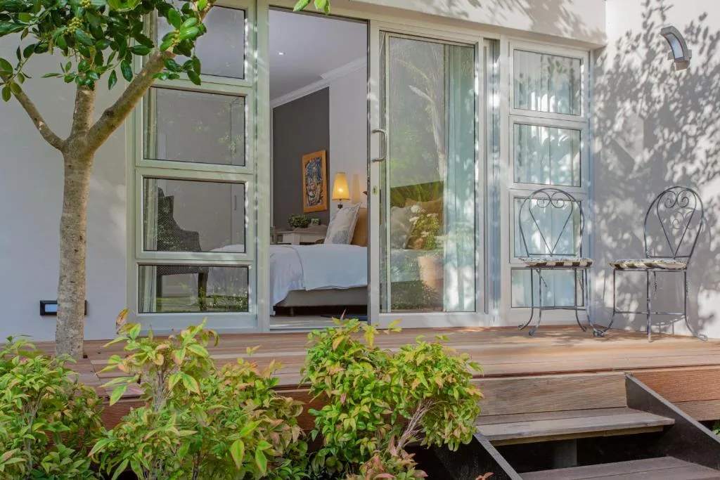 Wooden deck with seating chairs overlooking bedroom, garden landscaping visible